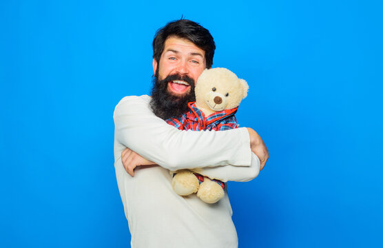 Teddy bear toy. Bearded man in white sweater hugging plush teddy bear toy. Present gift for birthday or anniversary. Holidays celebration. Satisfied happy man with beard cuddling fluffy teddy bear.