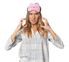 Blonde in pajamas with sleep mask screaming with rage.