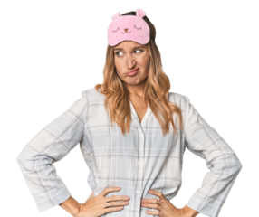 Blonde in pajamas with sleep mask confused, feels doubtful and unsure.