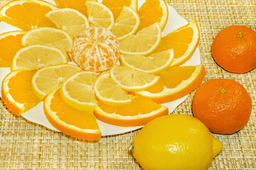 A dish of tangerine, orange slices and lemon