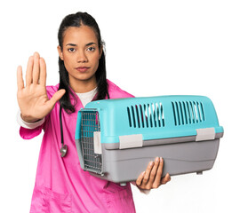 Young Filipina vet holding pet carrier standing with outstretched hand showing stop sign,...