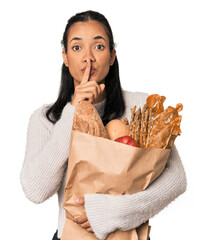 Young Filipina shopping for groceries keeping a secret or asking for silence.