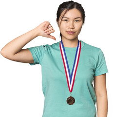 Chinese athlete showing a medal showing a dislike gesture, thumbs down. Disagreement concept.