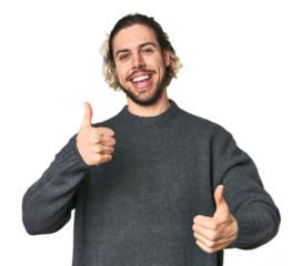 Young Caucasian man in studio setting raising both thumbs up, smiling and confident.