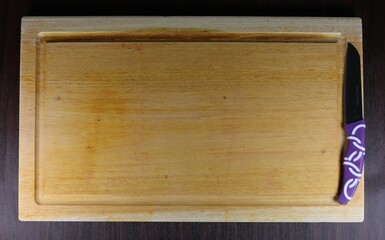 Close up of a knife on a wooden cutting board.