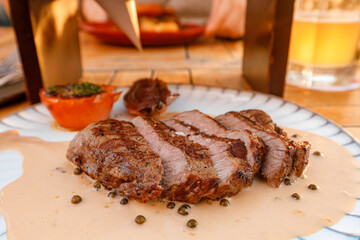 Grilled steak served with creamy sauce and garnish at an outdoor dining setting during sunset	