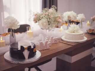 Elegant Black celebration cake with decoration, surrounded by soft tulle, candlelight, and fresh flower arrangements. Weding cake for groom and bride
