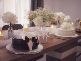 Elegant Black celebration cake with decoration, surrounded by soft tulle, candlelight, and fresh flower arrangements. Weding cake for groom and bride