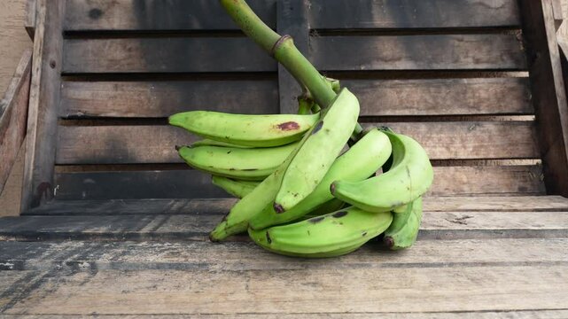 Fresh green plantain bunch on a rustic wooden crate showcasing tropical agriculture, healthy nutrition and organic produce.