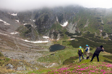 Backpackers paused at scenic overlook during challenging trek, surrounded by moody atmosphere and rugged terrain in high-altitude wilderness