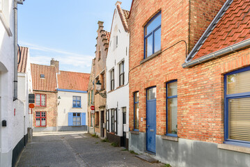 Cobbled street lined with traditional brick row houses in a historic city centre on a sunny summer day