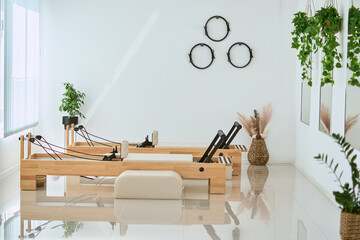 Bright and airy empty pilates studio without people. Beautiful space featuring wooden machine,...