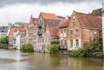 Historic brick houses along a river under stormy sky in summer