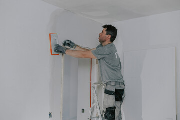 A young builder is plastering a doorway.