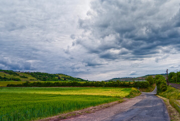 Road along fields, hills and clouds
