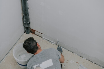 A young builder is plastering a wall on a landing.