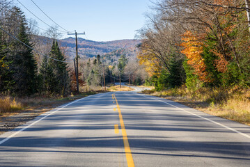 Empty winding road through a mountain valley at sunset in autumn