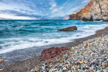 Amazing view of sea waves crashing on the shore and flowing above seashore pebbles