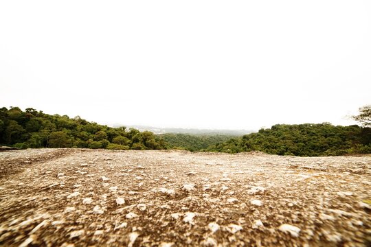 Pedra grande e vista de uma floresta e cidade ao fundo. 