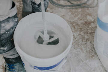 A young man beats putty with a construction mixer.