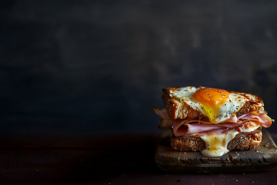Croque-madame traditionnel garni de jambon, fromage fondu et &oelig;uf au plat coulant sur pain grill&eacute;, pr&eacute;sentation gourmande sur fond rustique, sp&eacute;cialit&eacute; fran&ccedil;aise savoureuse et r&eacute;confortante