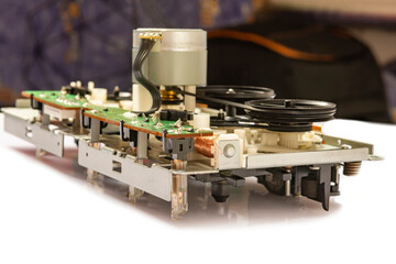 Close-up of the magnetic tape drive mechanism of an old double-cassette tape recorder on a white background. Close-up of the magnetic tape drive mechanism. Copy space