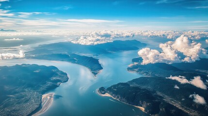 Aerial view shows mountains surrounded by water and puffy clouds