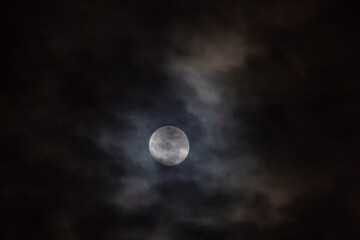 Full moon in the night sky with clouds. 