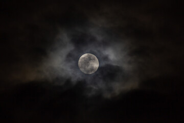 Full moon in the night sky with clouds. 