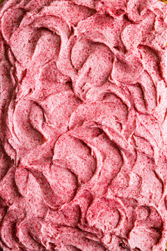 Close-up of textured pink frosting with a smooth, swirled pattern.