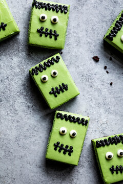 Halloween-themed brownies decorated to look like Frankenstein's monster with green icing and candy eyes.