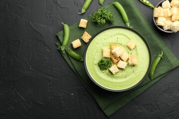 Tasty pea cream soup with croutons and broccoli served on black table, flat lay. Space for text