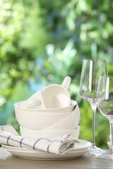 Different clean dishes on wooden table against blurred green background