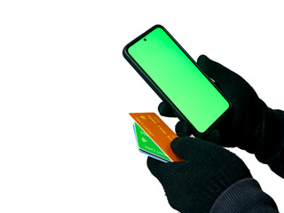 Cyber crime concepts. A male thief holds a smartphone and credit card in his hand and picks up a...