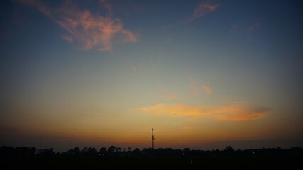 sunset in the rice fields with yellowing sky and silhouettes of the countryside and towers