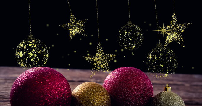 Fototapeta Showcasing large red and gold baubles glittering on wood table, with hanging gold star ornaments