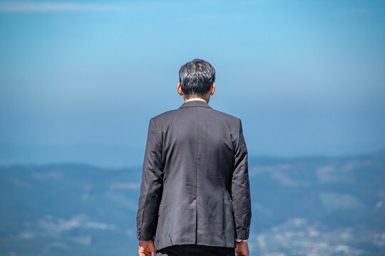 Man in suit facing distant mountains alone