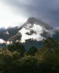 Evening light catching the side of mountains as clouds roll in.