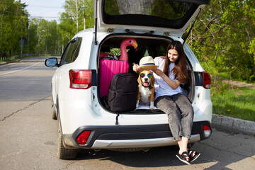 A young girl and a beagle dog are sitting in the trunk of a car.