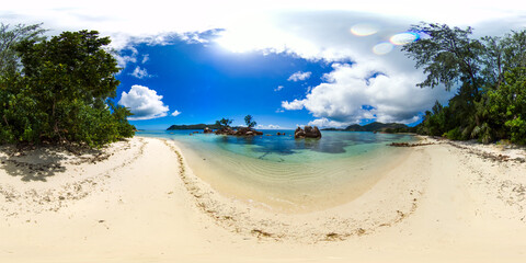 A serene beach scene with crystal-clear water, soft sand, and green foliage merging with the...