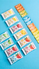 Fototapeta premium Playful flat lay of kids’ multivitamin sachets on bright blue backdrop—fun, colorful design that appeals to both children and parents in supplement packaging.