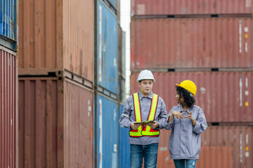 Engineer and foreman worker team in hardhat and safety vest checking containers box from cargo,...