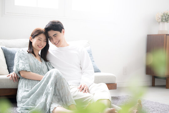 Young couple cuddling relaxing in living room with green foreground blur