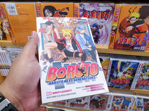 South Kalimantan, Indonesia - 06 09 2025 : Boruto manga volume held in hand with additional Japanese comics on shelf in background, ideal for editorial or otaku lifestyle themes