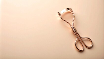 ソフトなマットベージュ背景に配置されたローズゴールドのアイラッシュカーラーの上品な輝き


