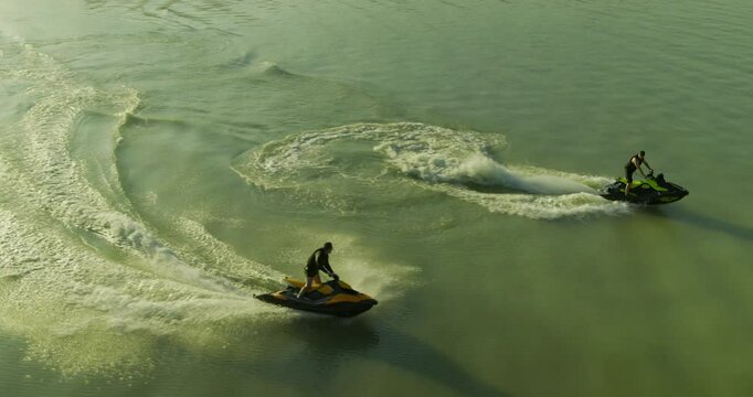 Epic drone shot following jet skiers doing tricks on beautiful lake at sunrise
