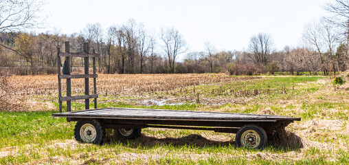 A flat, wooden farm wagon in a farm field in Columbus, Pennsylvania, USA on a sunny spring day