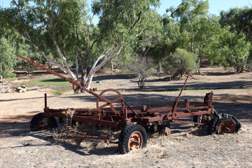 Vintage, old, rusty agriculture, farming equipment abandoned in remote Australian Outback, amongst Eucalyptus trees. History, nostalgia, scrap, collection, travel and tourism