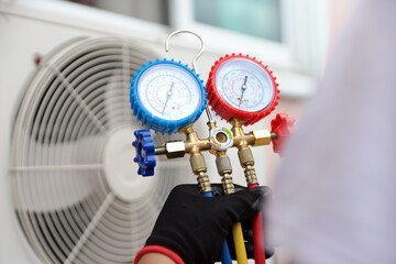 Air conditioning electrical technician using manifold gauge measuring tool checking refrigerant...