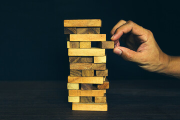 Close-up hand prevents and choose wooden block not falling concepts of financial risk management and strategic planning and business challenge plan or safety insurance.
